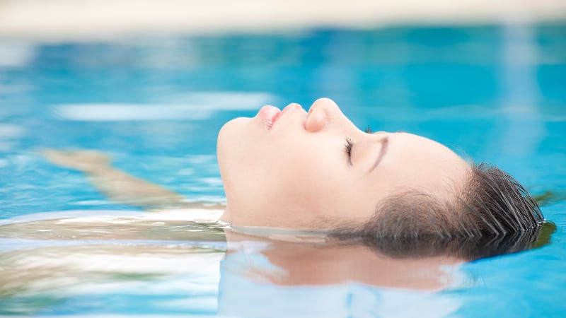 Woman floating on her back in a swimming pool