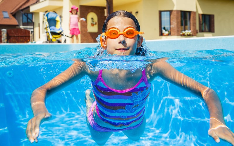 Girl in swimming pool poking her head out of the water