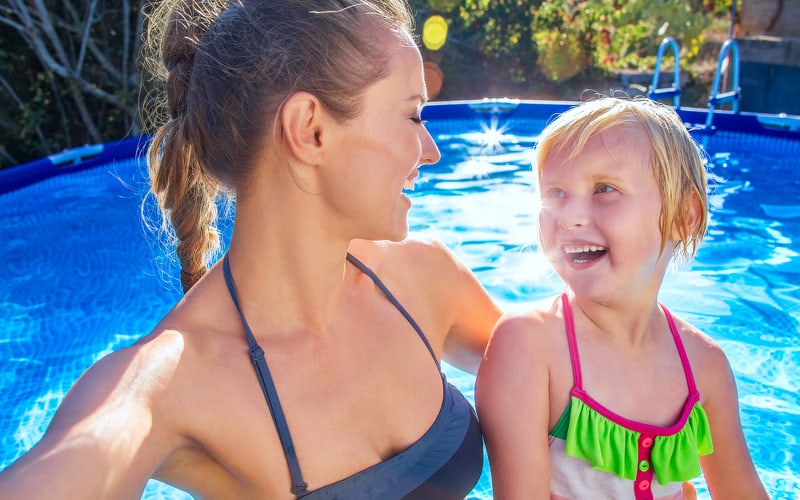 Mother with daughter in an above ground swimming pool