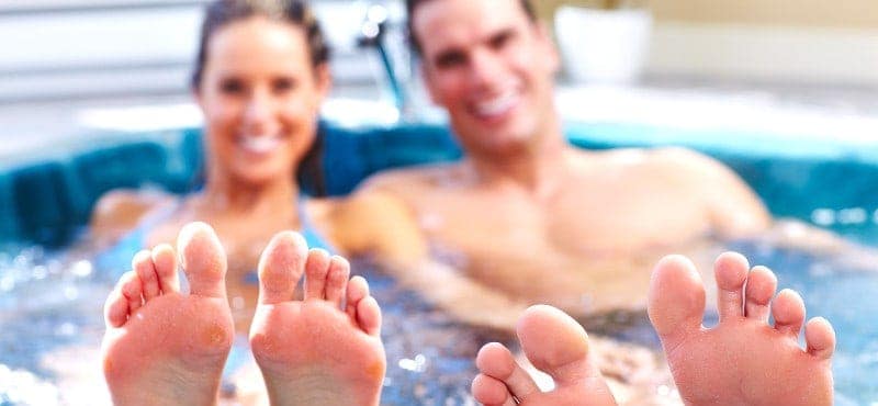 Man and woman relaxing in a hot tub/spa with their feet in the foreground