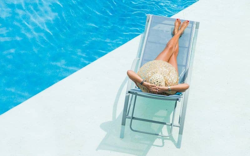 Woman relaxing on the deck of a luxury swimming pool