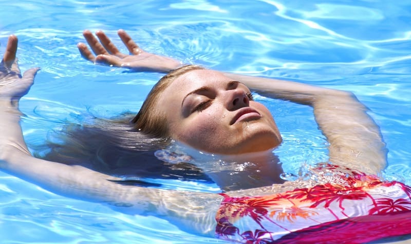Woman relaxing in a swimming pool with eyes closed