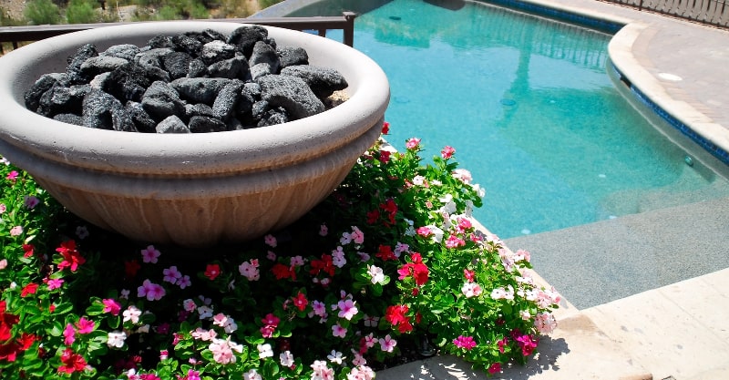 Fire bowl and colorful flowers near an inground swimming pool