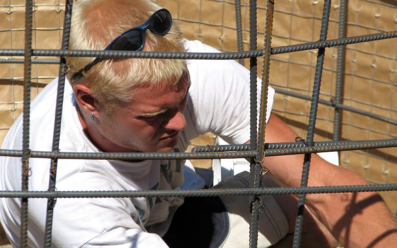 Closeup of a man working on rebar as part of inground pool installation