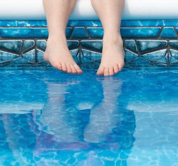 Feet dangling in swimming pool