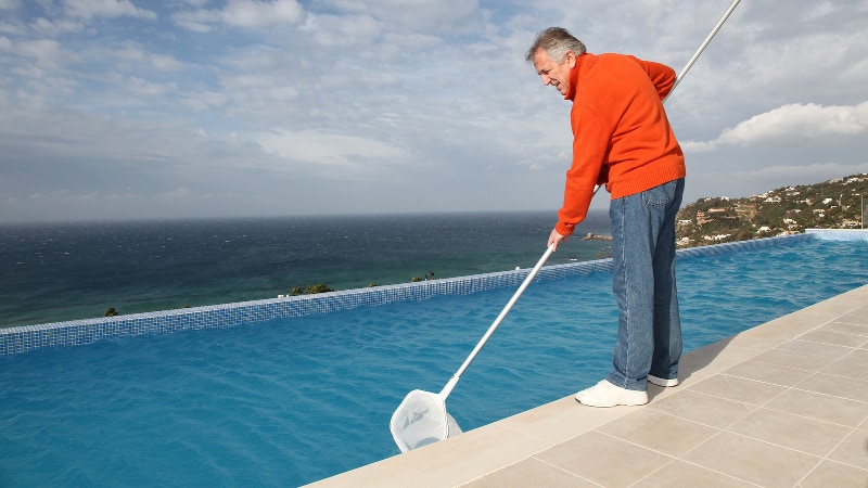 Man skimming leaves out of a swimming pool