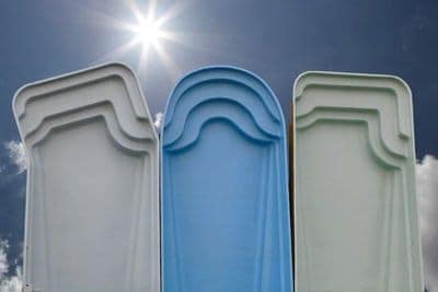 Three fiberglass swimming pool shells standing up on one end