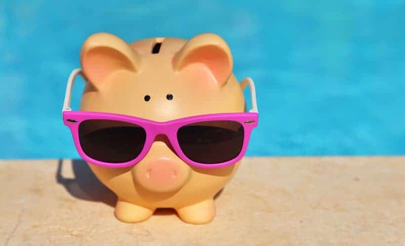 Piggy bank sitting on the deck of an inground swimming pool