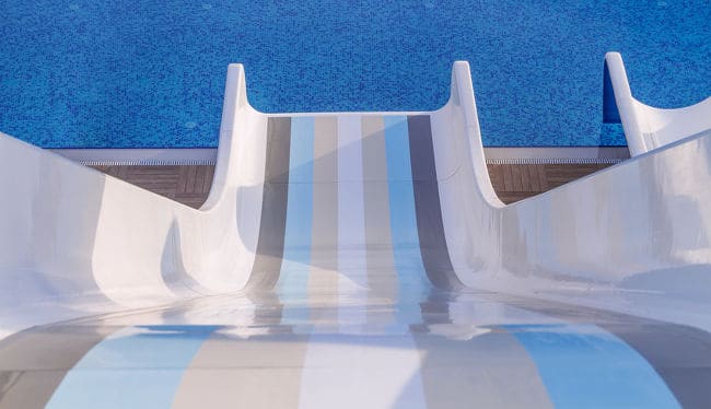 POV shot of a rainbow-colored pool slide