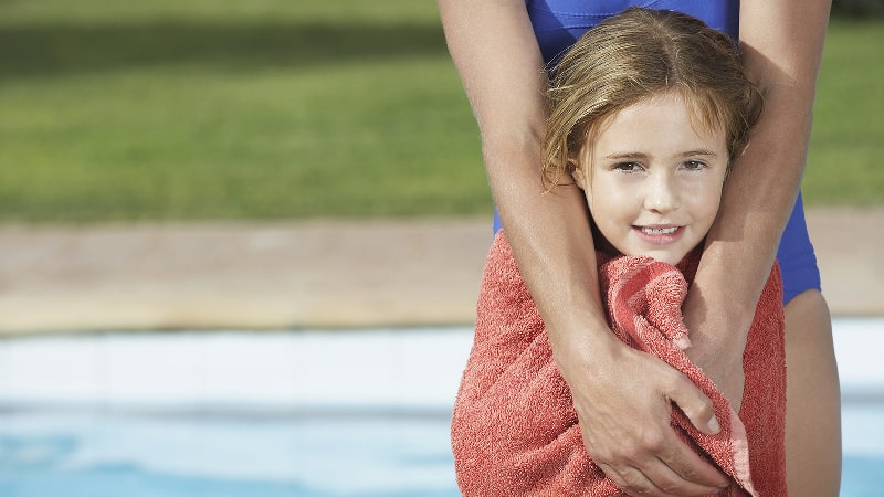 Little girl wrapped in a towel and shivering after being in the pool