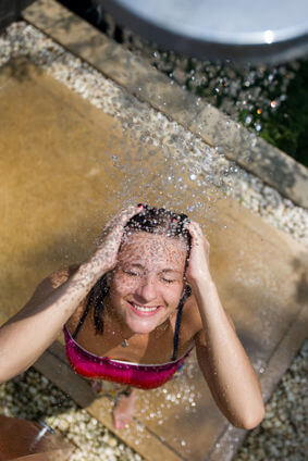 Girl in swimsuit enjoying an outdoor pool shower