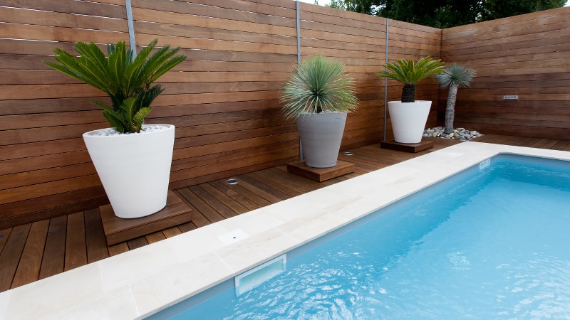 Wooden pool fence surrounding an inground swimming pool