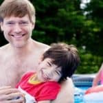 Man holding a disabled child in a swimming pool