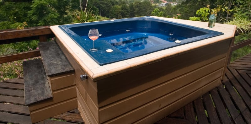 Hot tub/spa sitting in the nook of a wooden deck, with a view of the mountains in the background