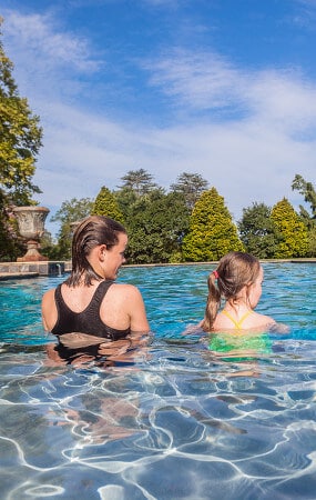 Two young girls standing in an inground swimming pool at the edge of a baja shelf