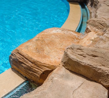 Closeup of a diving rock on the edge of an inground swimming pool