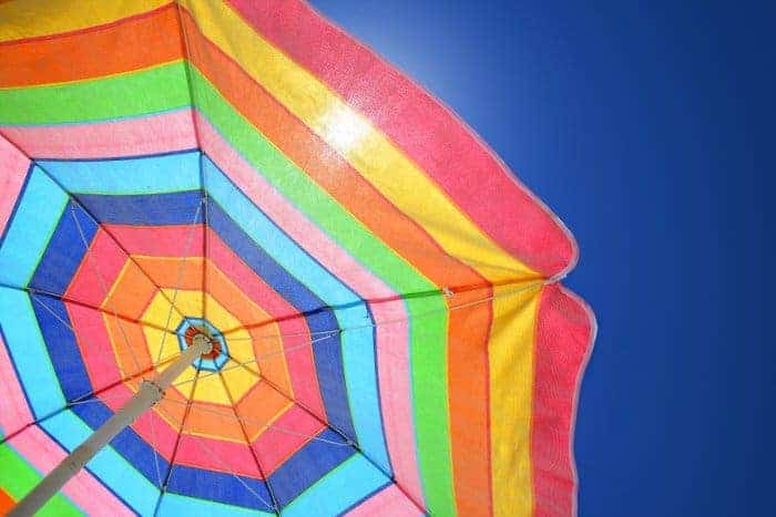 View from underneath a rainbow colored pool umbrella on a sunny day