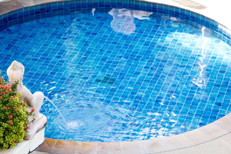 Small swimming pool with a statue fountain on the pool deck