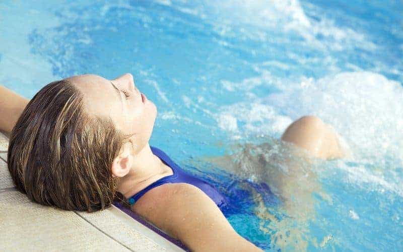 Young woman leaning back and relaxing in a spool pool (spa swimming pool combo)