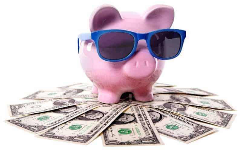 Piggy bank with sunglasses sitting on one dollar bills