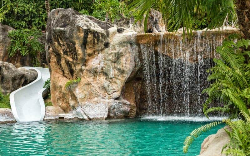 Swimming pool with slide, cave/grotto, and waterfall