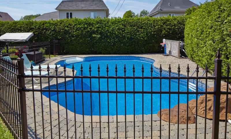 Closeup of a wrought iron fence with swimming pool in the background