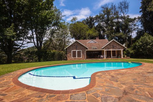 Kidney shaped inground pool near a cottage in the country