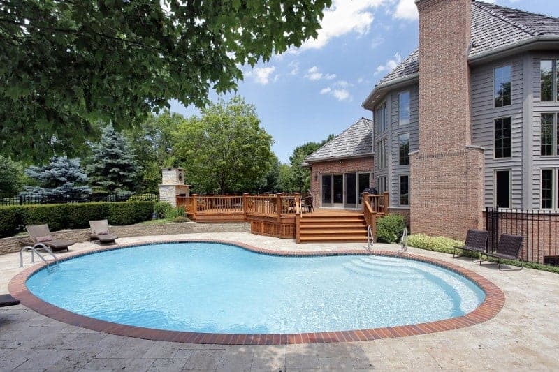 Residential inground kidney shaped swimming pool in a backyard