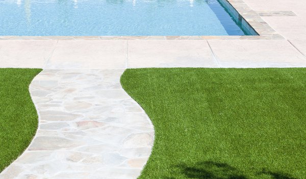 Artificial grass by a walkway to an inground swimming pool