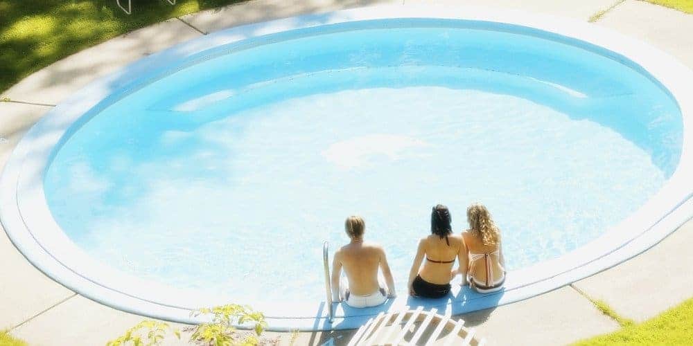 Group of people sitting around a round swimming pool on a summer day