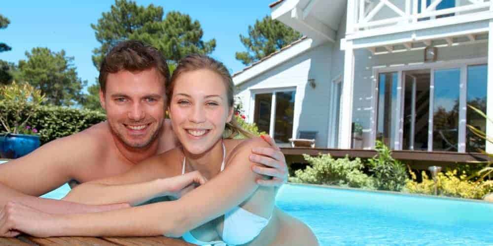 Closeup of a young couple smiling while soaking in an inground swimming pool