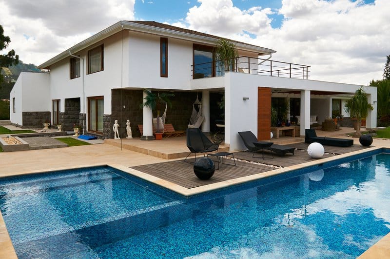 L-shaped inground swimming pool next to a modern home