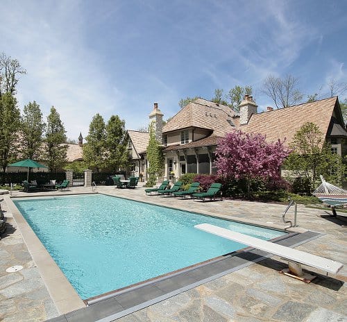 Rectangular inground swimming pool next to an upscale home