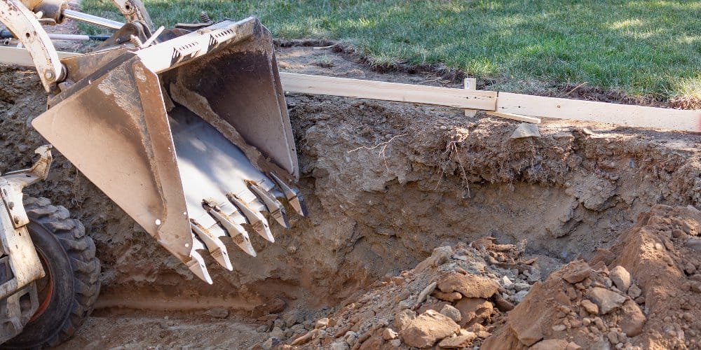 Bulldozer or backhoe excavating ground for installation of a recessed swimming pool