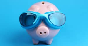 Piggy bank wearing swim goggles in front of a blue background