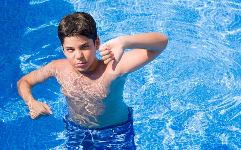 Adolescent boy in a pool giving the thumbs down