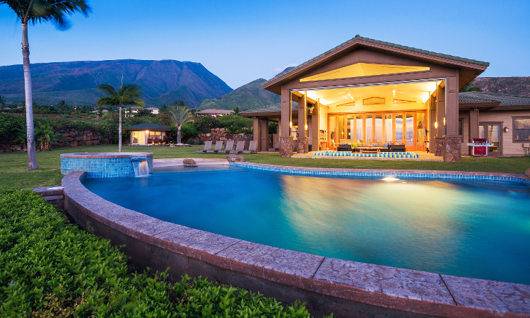 An upscale semi inground pool outside of a luxury home